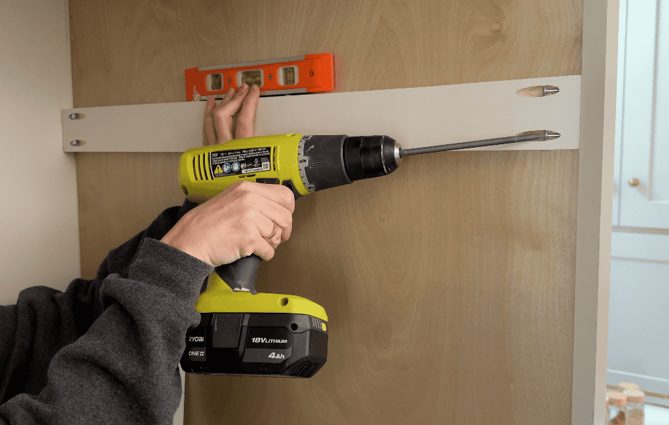 hanging 1x3 support board within refrigerator cabinet pocket so i can hang heavy things on side of fridge panel. drilling into face frame